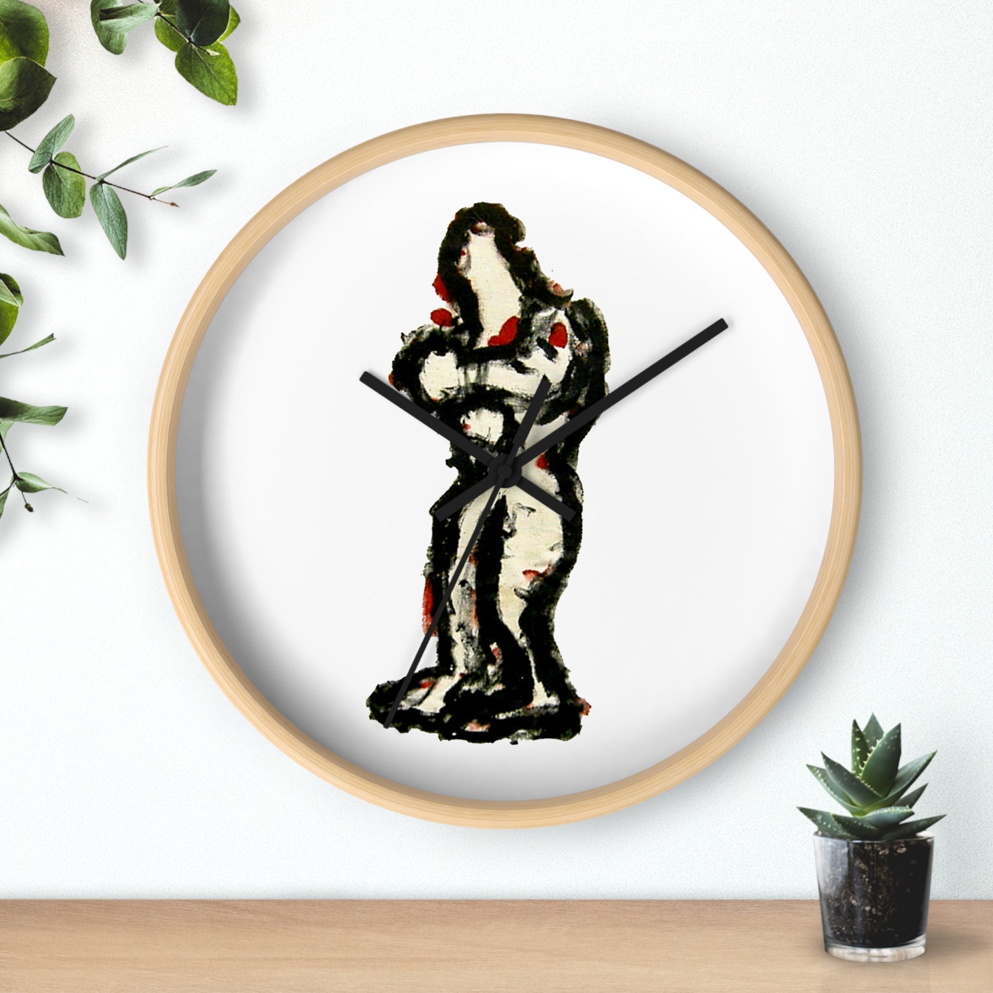 Abstract art wall clock with hand-painted In-Tense black and red standing figure on a white clock face in a light wood frame, sitting on a shelf beside a small plant.